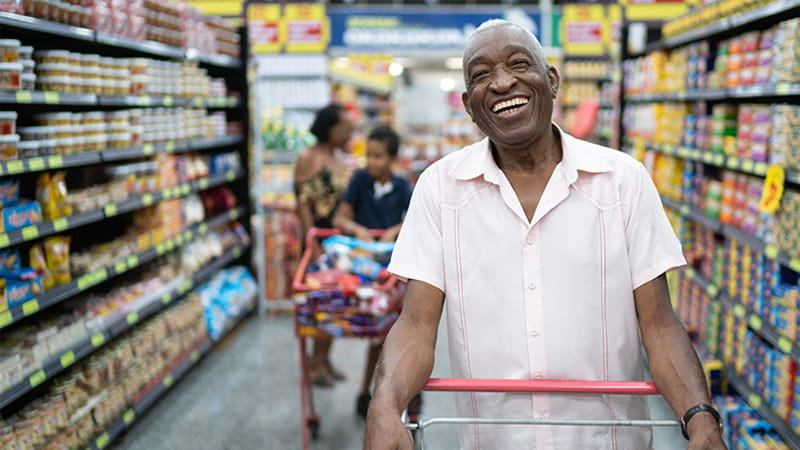An older Black couple is shopping with their grandkids down a grocery aisle.