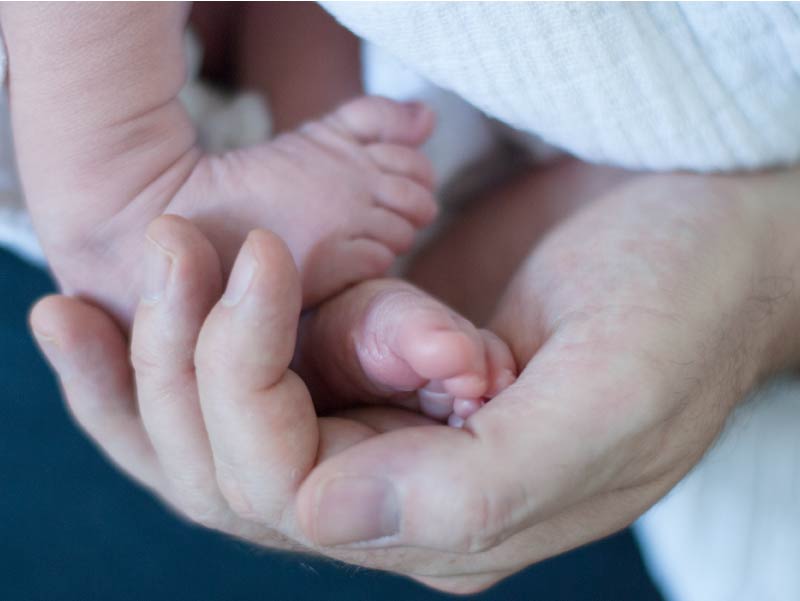 Woman holding newborn's feet.