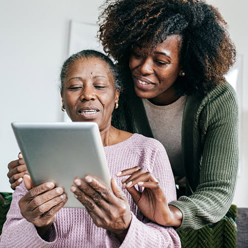 An older Black woman and her daughter are looking at a tablet.